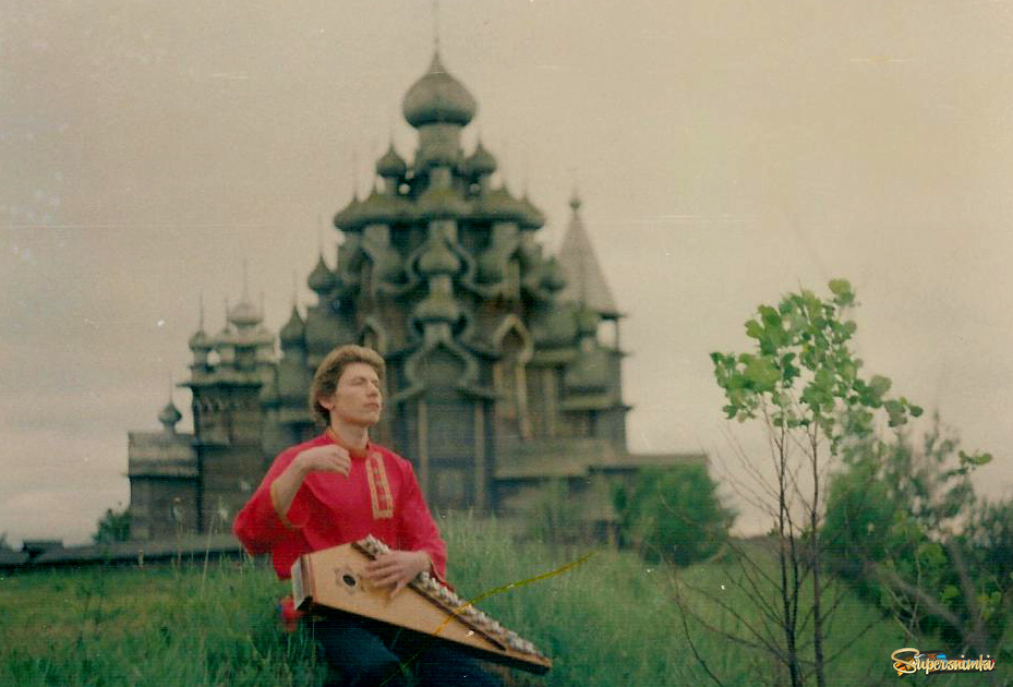 Мололдой Гусляр Иван Самоваров на фоне Храма в Кижах